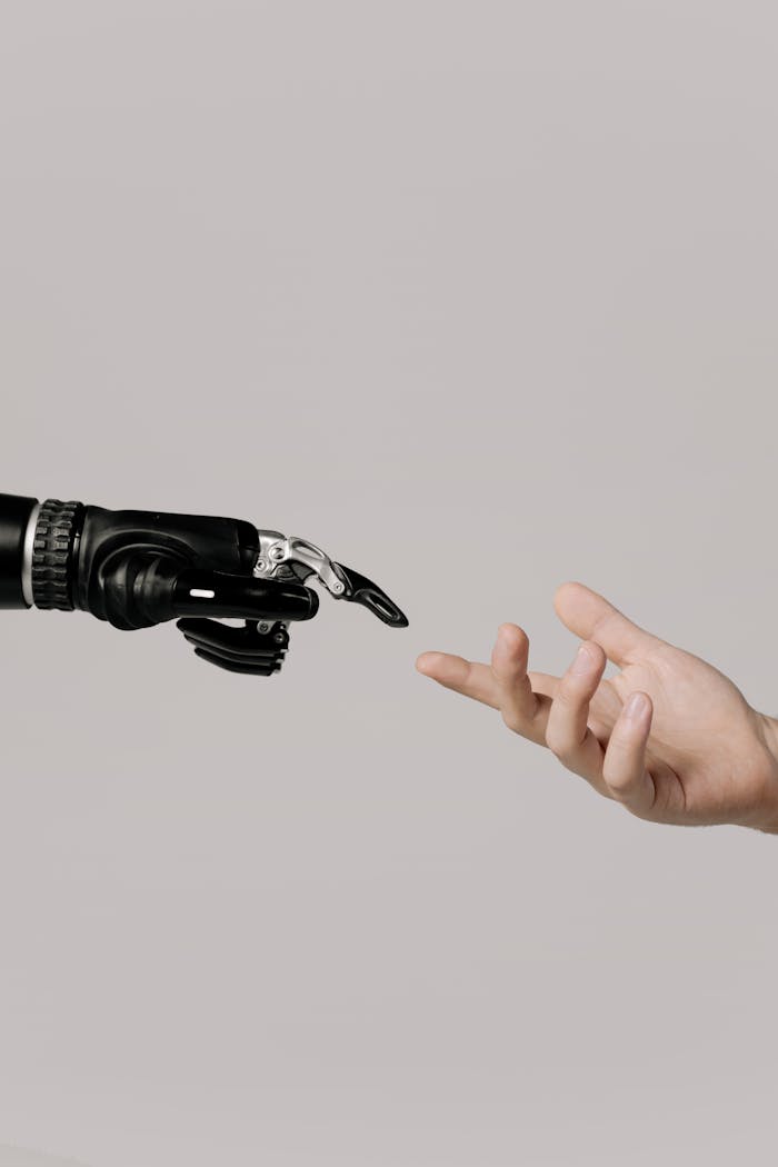 our-services-2 A human hand reaching to touch a bionic prosthetic hand on a white background.